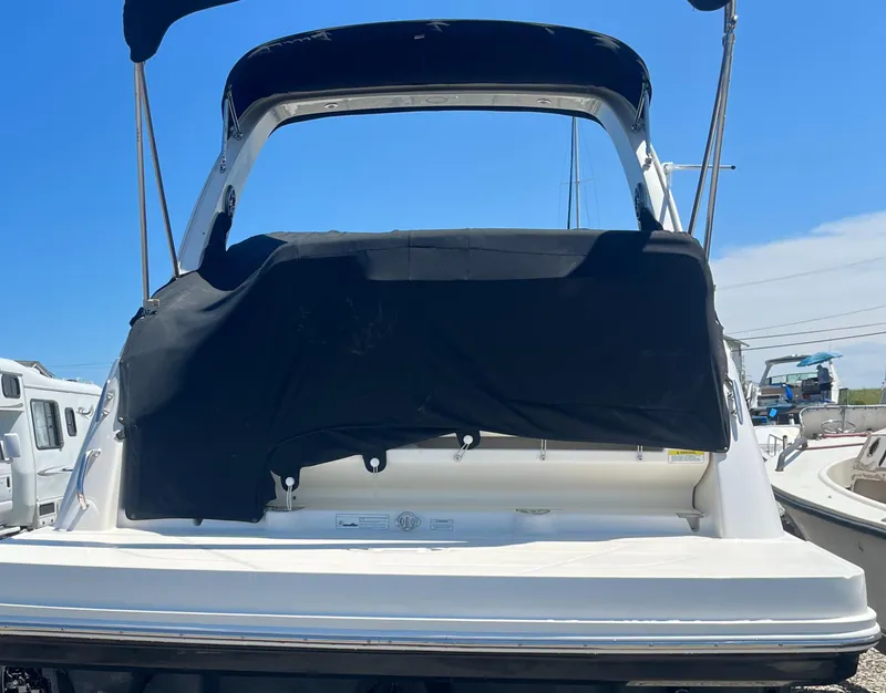 Slide: The Image of 2014 Sea Ray 260 Sundancer boat with black cover, docked under clear blue sky. - 5