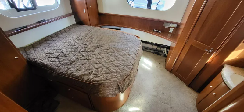 Slide: The Image of 2007 Silverton 43 Motor Yacht bedroom with quilted bedspread and wooden cabinetry. - 20