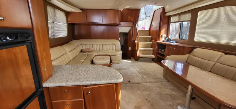 Slide: The Image of 2007 Silverton 43 Motor Yacht interior with beige seating, wooden cabinetry, and carpeted flooring. - 3