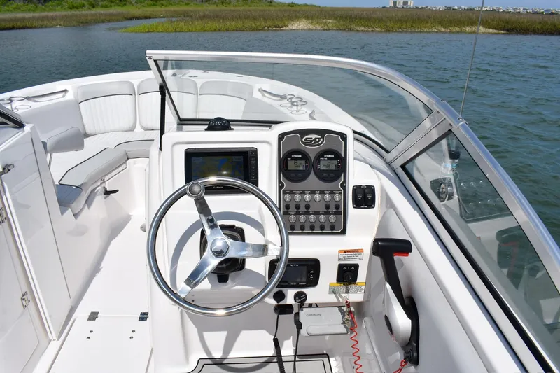Slide: The Image of 2020 Sea Fox 226 Traveler boat dashboard with steering wheel and controls on a calm waterway. - 6