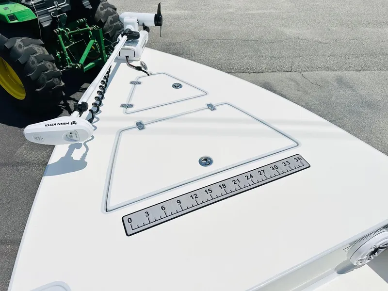 Slide: The Image of 2022 Hewes Redfisher 18 boat deck with ruler and trolling motor, parked near a tractor. - 10