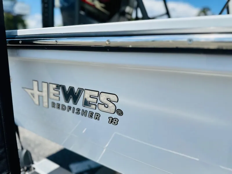 Slide: The Image of 2022 Hewes Redfisher 18 boat, close-up of logo on white hull. - 16