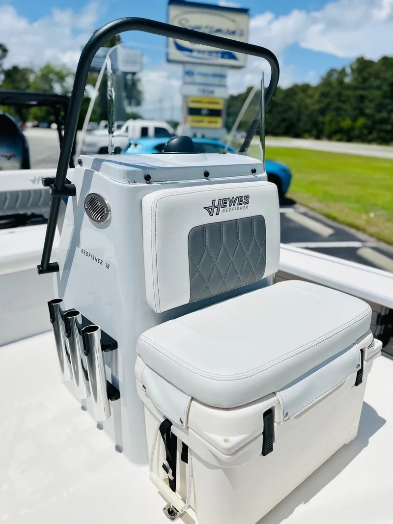 Slide: The Image of 2022 Hewes Redfisher 18 boat console with seating and rod holders, parked outdoors. - 7