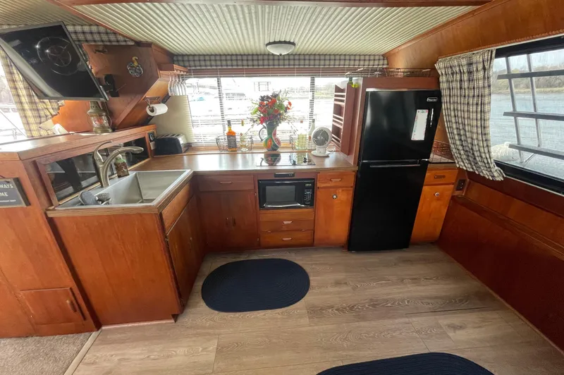 Slide: The Image of 1984 Bluewater 42 Coastal Cruiser kitchen with wood cabinetry, black fridge, and window view. - 35
