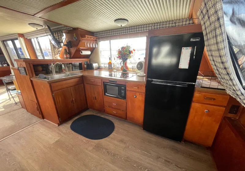 Slide: The Image of 1984 Bluewater 42 Coastal Cruiser kitchen with wood cabinetry, black fridge, and microwave. - 42