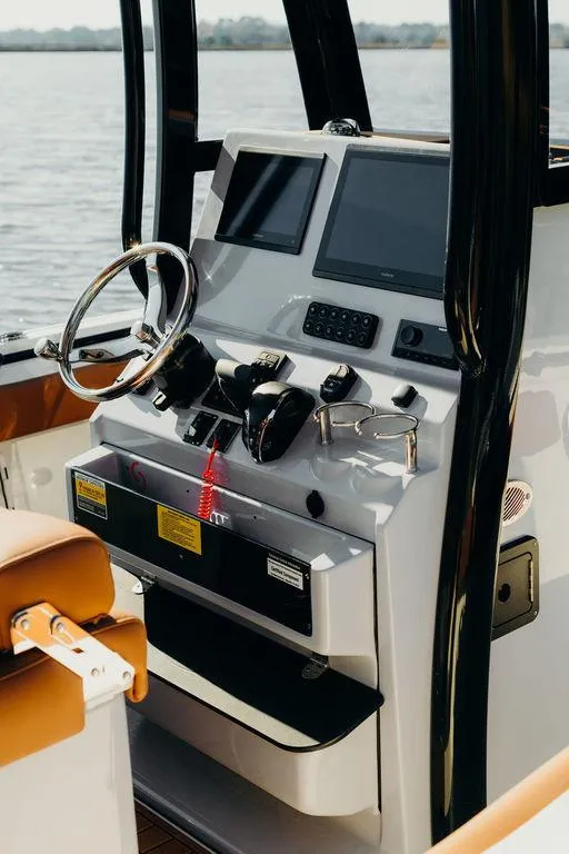 Slide: The Image of 2025 Key West 239FSR boat console with dual screens and steering wheel on calm water. - 10
