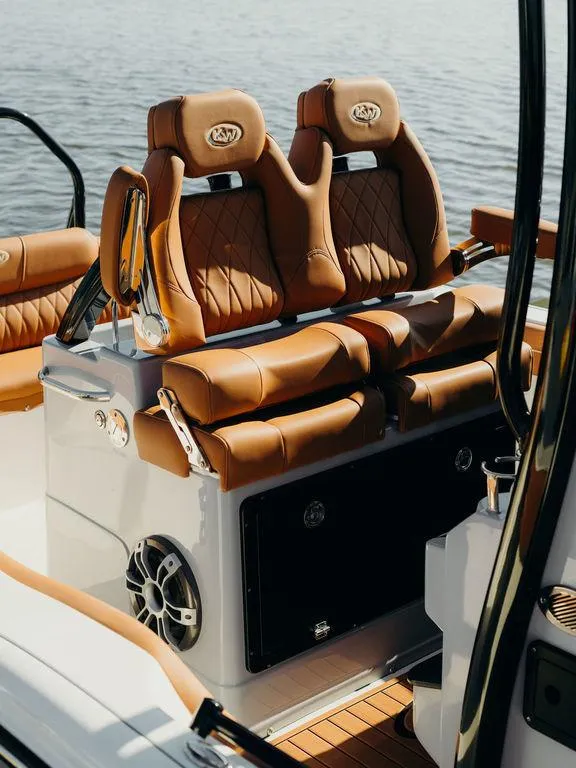 Slide: The Image of 2025 Key West 239FSR boat seats with luxurious brown leather upholstery on a calm water backdrop. - 13