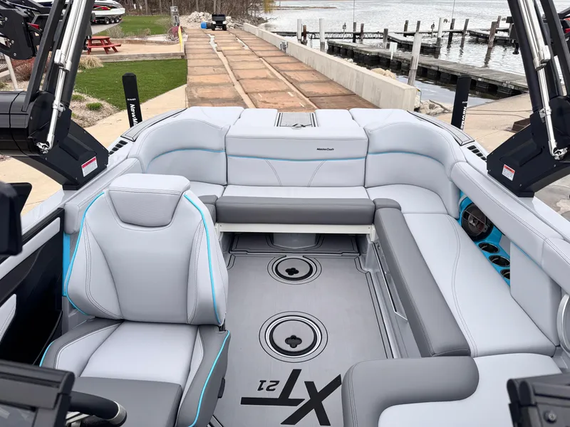 Slide: The Image of 2022 MasterCraft XT21 boat interior with sleek seating and modern design at a dock. - 11