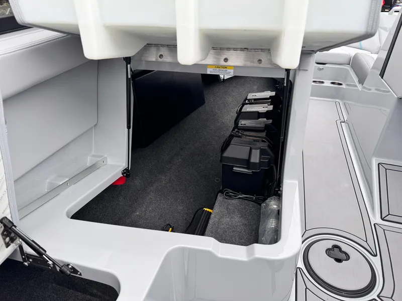 Slide: The Image of 2022 MasterCraft XT21 boat interior storage compartment with battery setup and carpeted flooring. - 26