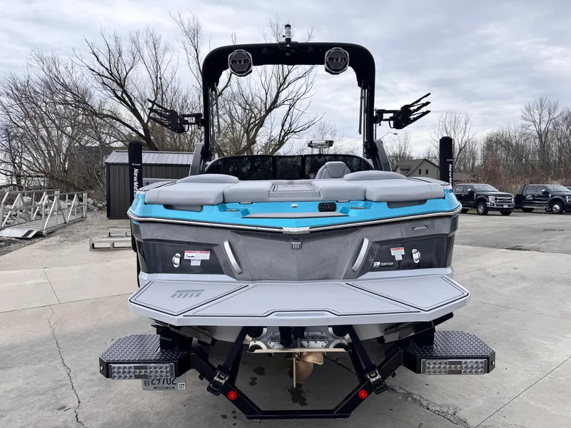 Slide: The Image of 2022 MasterCraft XT21 boat with blue and gray accents, parked outdoors on a cloudy day. - 3