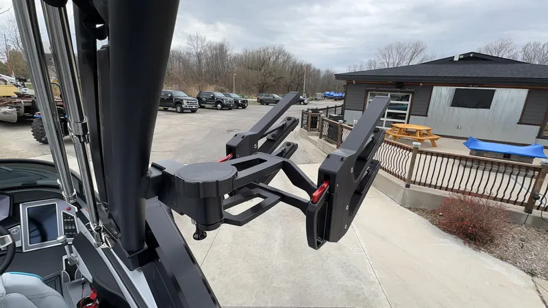 Slide: The Image of 2022 MasterCraft XT21 boat with wakeboard rack, parked near a building and vehicles. - 5