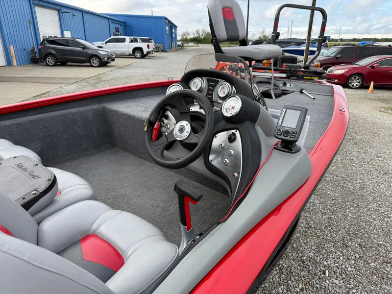 Slide: The Image of 2016 Tracker Pro Team 175 TXW boat interior with steering wheel and gauges, parked near blue building. - 5