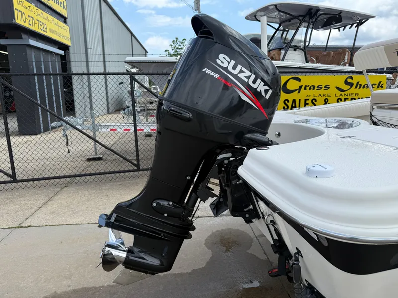 Slide: The Image of 2015 Carolina Skiff 19 Sea Skiff with Suzuki outboard motor, parked near a sales shop. - 32