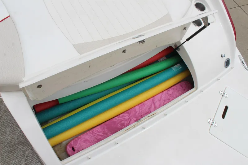 Slide: The Image of 2007 Rinker 246 Captiva Bowrider storage compartment with colorful pool noodles. - 17
