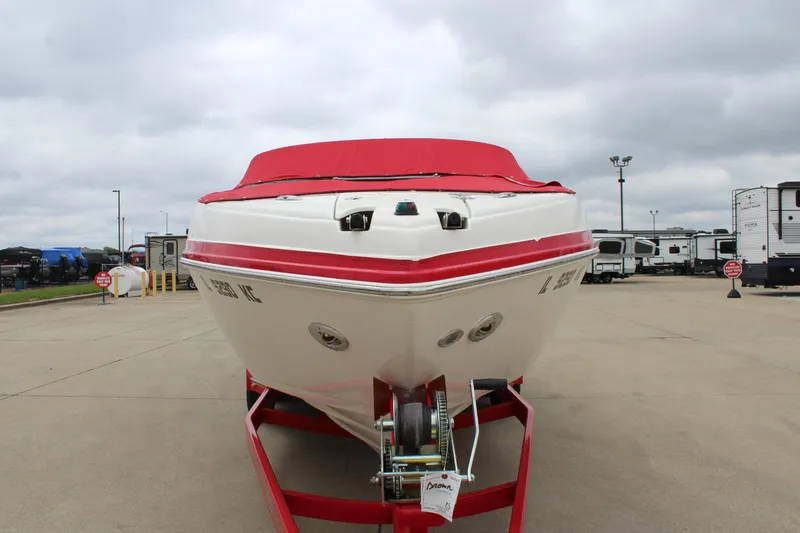 Slide: The Image of 2007 Rinker 246 Captiva Bowrider with red cover on trailer, parked outdoors. - 2