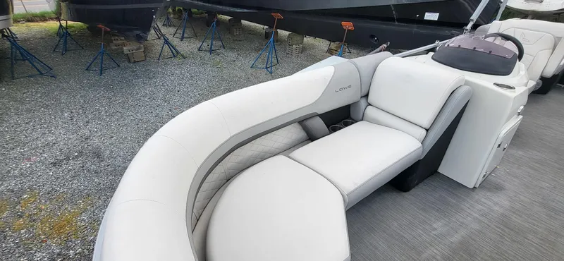 Slide: The Image of 2022 Lowe SS 210 boat interior with white seating on gravel lot. - 12