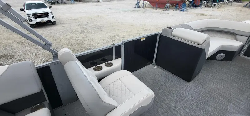 Slide: The Image of 2022 Lowe SS 210 pontoon boat interior with beige seating and cup holders. - 6