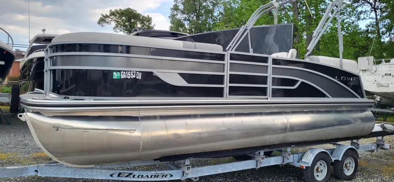Slide: The Image of 2022 Lowe SS 210 pontoon boat on trailer, sleek design, parked outdoors. - 8