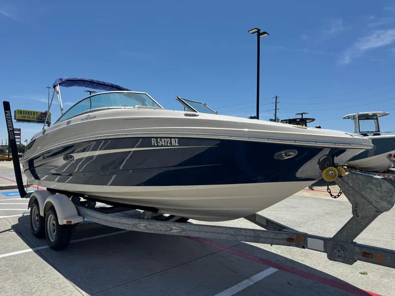 Slide: The Image of 2010 Sea Ray 220 Sundeck boat on trailer under clear blue sky. - 11