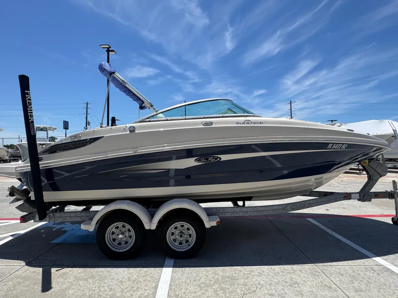 Slide: The Image of 2010 Sea Ray 220 Sundeck boat on trailer under clear blue sky. - 12