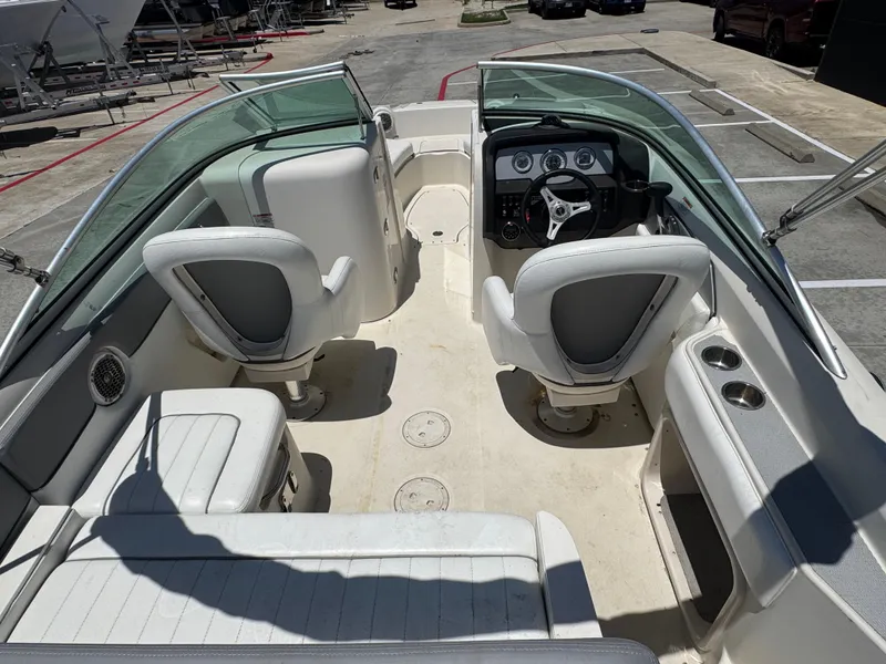 Slide: The Image of 2010 Sea Ray 220 Sundeck interior with seating and steering wheel, parked in a lot. - 16