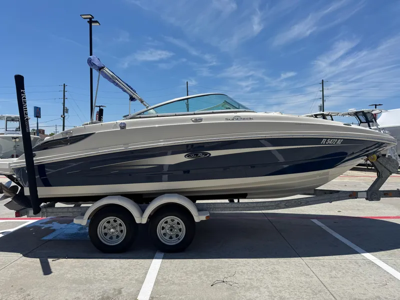 Slide: The Image of 2010 Sea Ray 220 Sundeck boat on trailer under clear blue sky. - 23