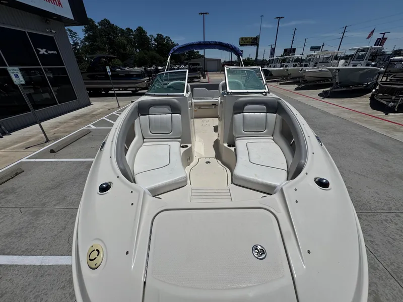 Slide: The Image of 2010 Sea Ray 220 Sundeck boat with spacious seating, displayed at a dealership. - 8