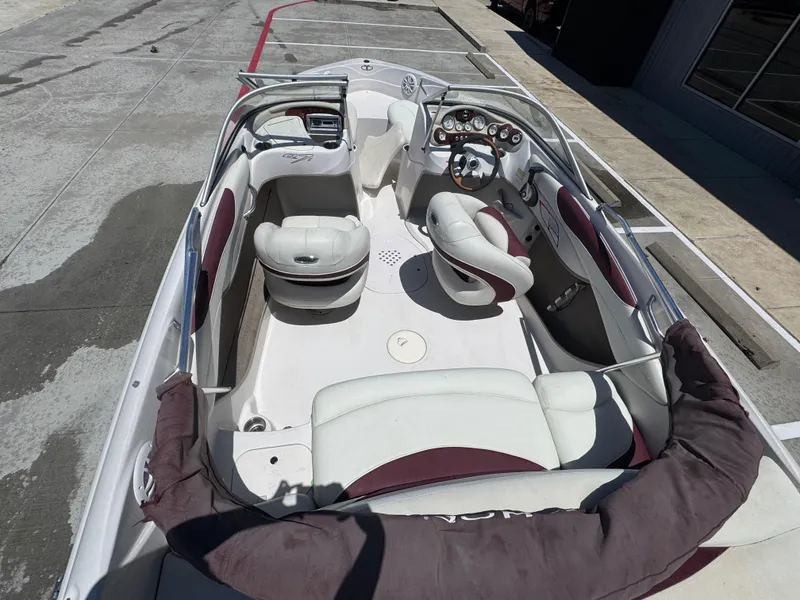 Slide: The Image of 2015 TAHOE WRMG Q7I boat interior with white and maroon seating, parked on concrete. - 10
