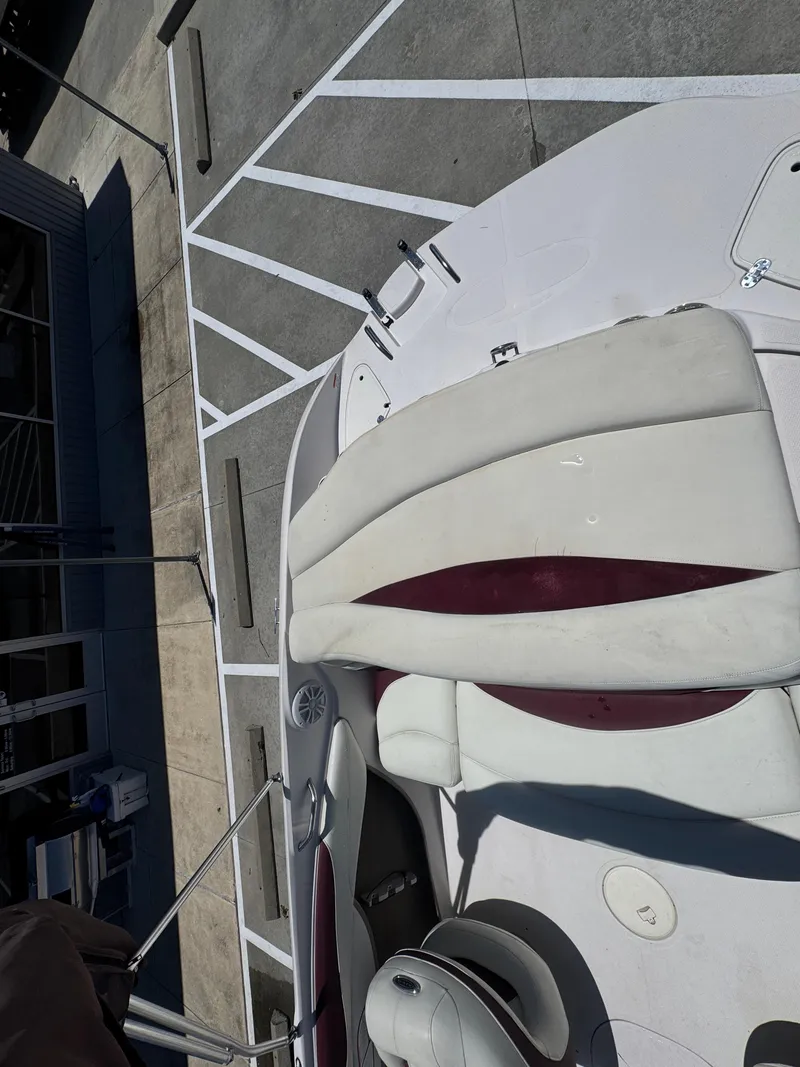 Slide: The Image of 2015 TAHOE - WRMG Q7I boat interior with white and maroon seating, parked on concrete. - 23