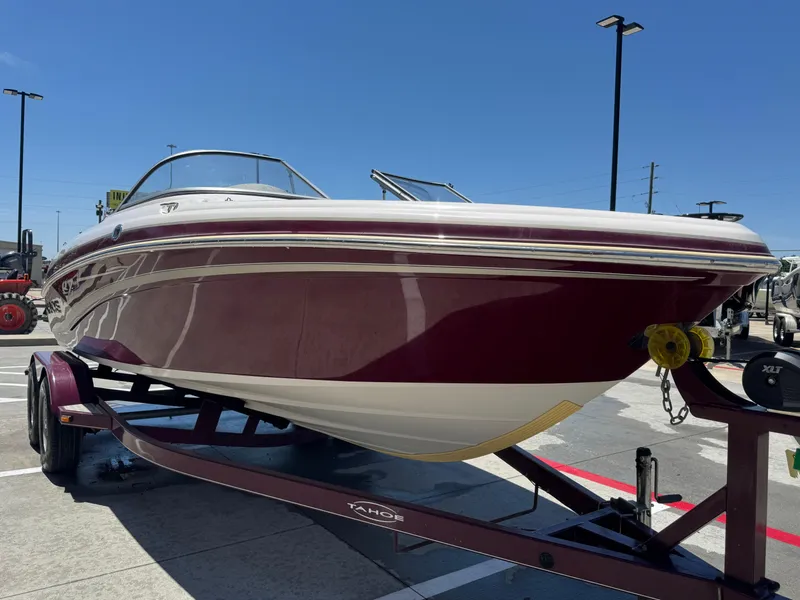 Slide: The Image of 2015 TAHOE Q7I boat on trailer, maroon and white, parked outdoors under clear sky. - 5