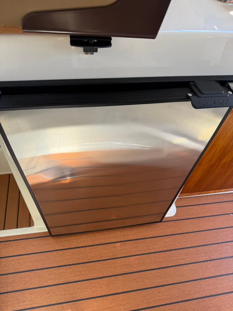 Slide: The Image of 2023 Ranger Tugs R-25 interior with stainless steel fridge and wood flooring. - 12
