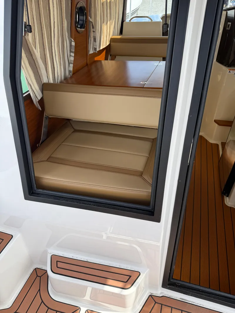 Slide: The Image of 2023 Ranger Tugs R-25 interior with tan seating and wood flooring. - 15