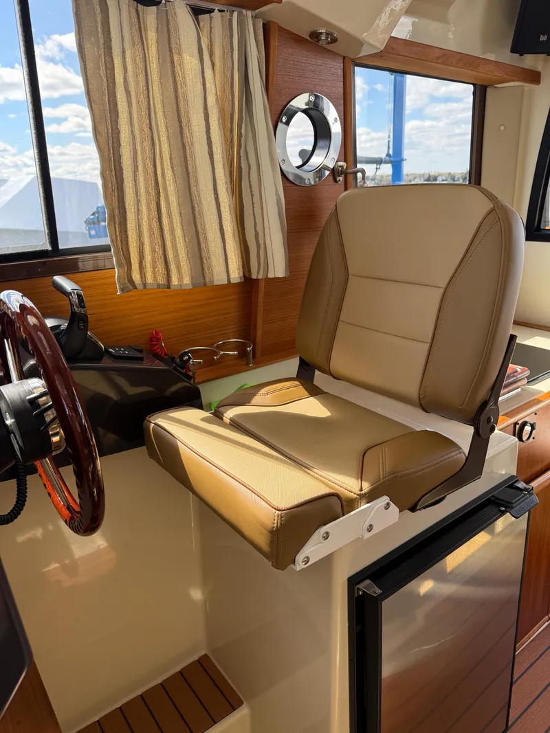 Slide: The Image of 2023 Ranger Tugs R-25 interior helm with tan seat and wooden accents. - 17