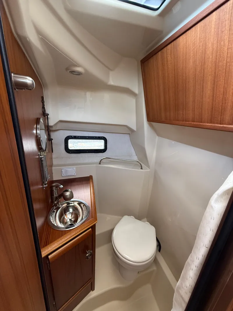 Slide: The Image of 2023 Ranger Tugs R-25 boat bathroom with wood cabinetry and stainless steel sink. - 20