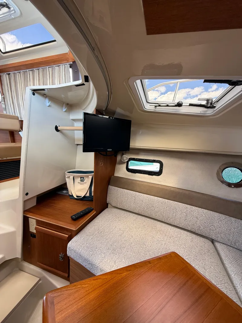 Slide: The Image of 2023 Ranger Tugs R-25 interior with cozy seating, TV, and skylight. - 21