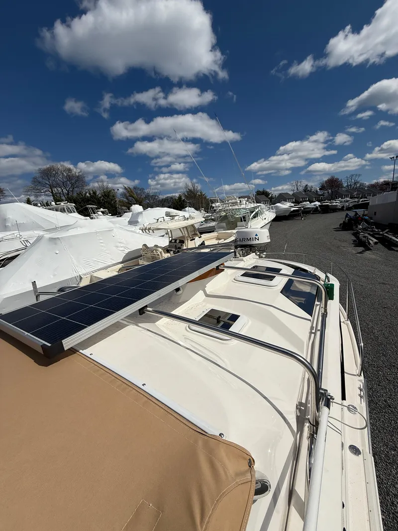 Slide: The Image of 2023 Ranger Tugs R-25 boat with solar panel, docked under a blue sky with clouds. - 24