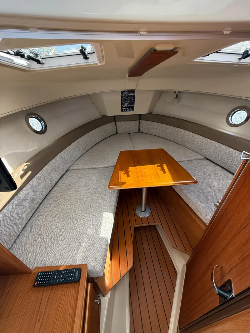 Slide: The Image of 2023 Ranger Tugs R-25 interior with cozy seating and wooden table. - 9