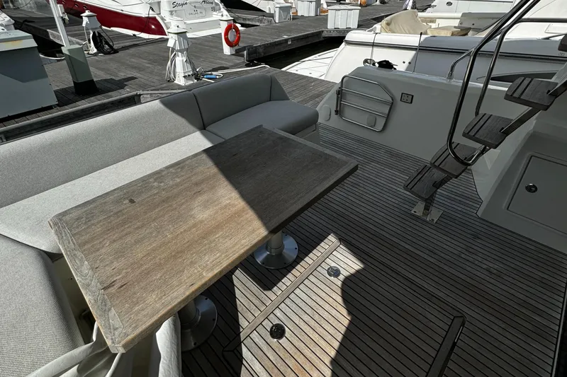 Slide: The Image of Prestige 460 Fly Bridge 2019 yacht deck with seating and wooden table. - 5