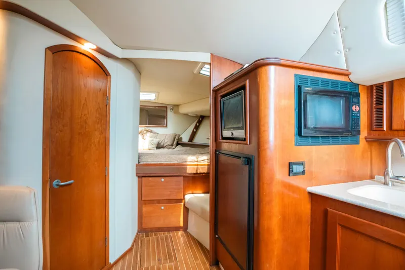 Slide: The Image of 2007 Rampage 38 Express yacht interior with wood finishes, kitchenette, and cozy sleeping area. - 30