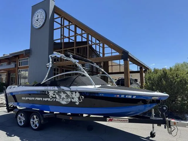 Slide: The Image of 2008 Nautique 230 Team Edition boat on trailer, parked outside a modern building. - 12