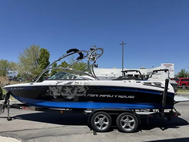 Slide: The Image of 2008 Nautique 230 Team Edition boat on trailer, blue and black design, parked outdoors. - 4