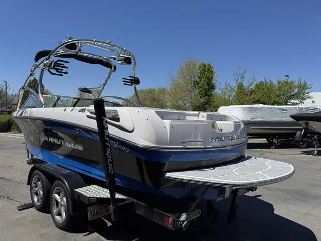 Slide: The Image of 2008 Nautique 230 Team Edition boat on trailer, blue and white, parked outdoors. - 5