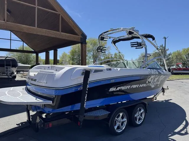 Slide: The Image of 2008 Nautique 230 TEAM EDITION boat on trailer, parked outdoors under a wooden shelter. - 7