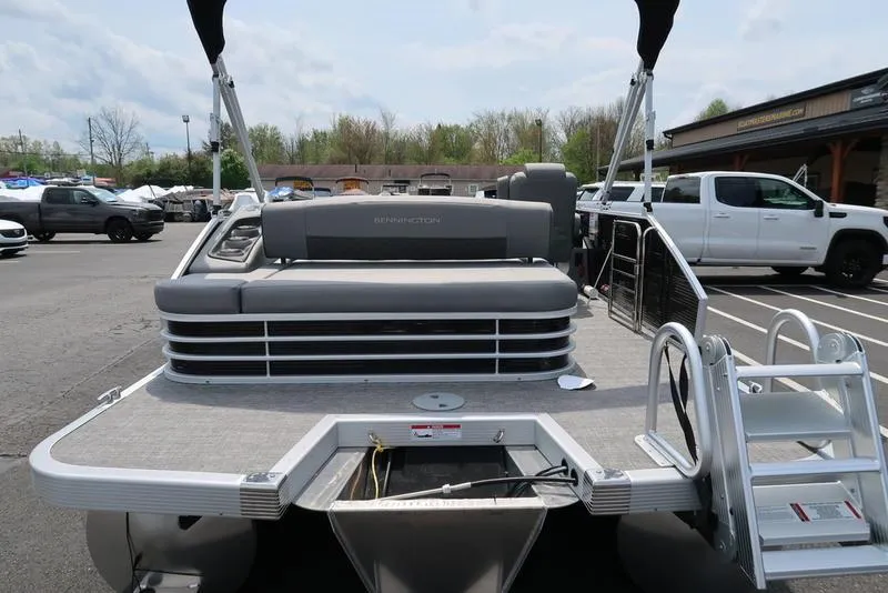 Slide: The Image of 2025 Bennington L Swingback 23 LSB pontoon boat with rear seating and ladder in a parking lot. - 5
