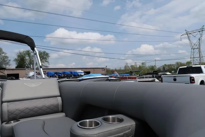 Slide: The Image of 2025 Bennington L Swingback 23 LSB pontoon boat interior with cup holders, parked outdoors. - 6