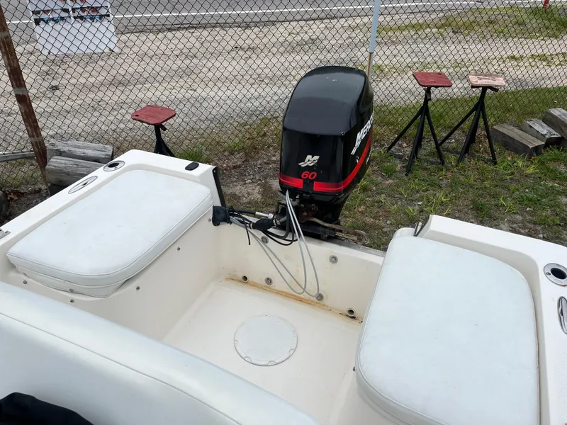 Slide: The Image of 2006 Key West 1720 Center Console boat with outboard motor, parked near a chain-link fence. - 8