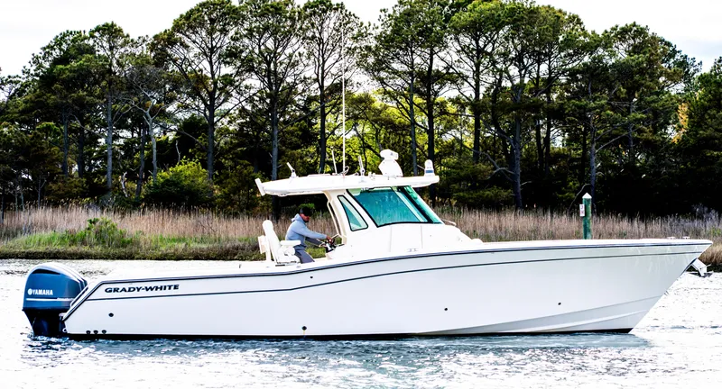 Slide: The Image of 2015 Grady-White Canyon 376 boat cruising on a calm waterway with trees in the background. - 3