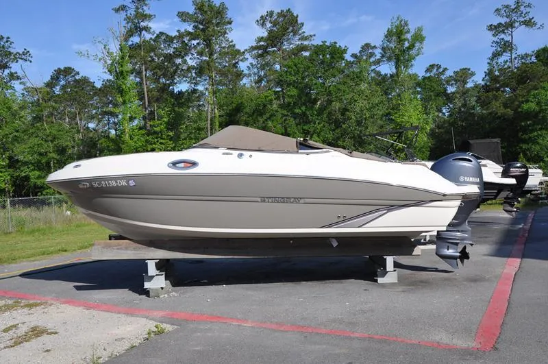 Slide: The Image of 2018 Stingray 214 LR boat on trailer, parked outdoors with trees in background. - 1