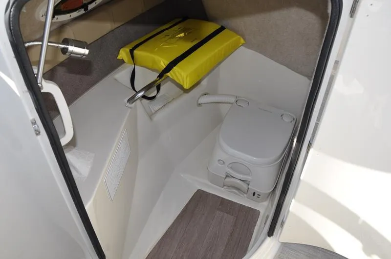 Slide: The Image of 2018 Stingray 214 LR boat interior with portable toilet and life jacket storage. - 19