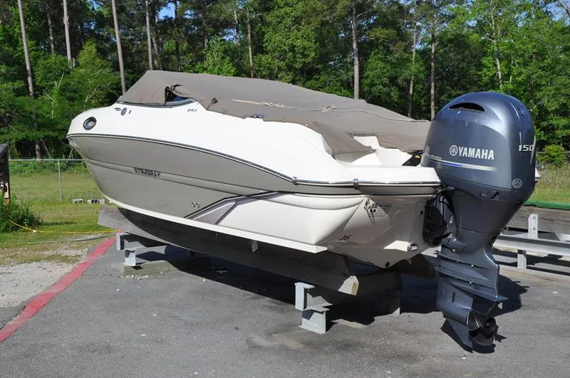 Slide: The Image of 2018 Stingray 214 LR boat with Yamaha 150 engine, covered and on a stand outdoors. - 2
